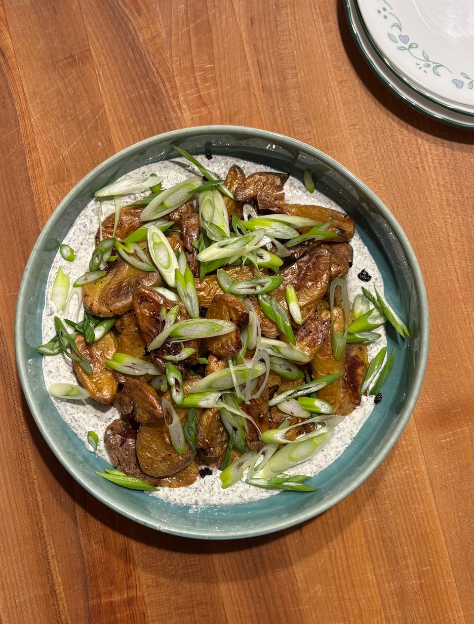 Smashed potatoes on top of a roasted seaweed sour cream and topped with diagonally-sliced scallions.