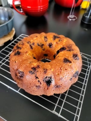 A blueberry-lemon bundt cake on a cooling rack on a black counter