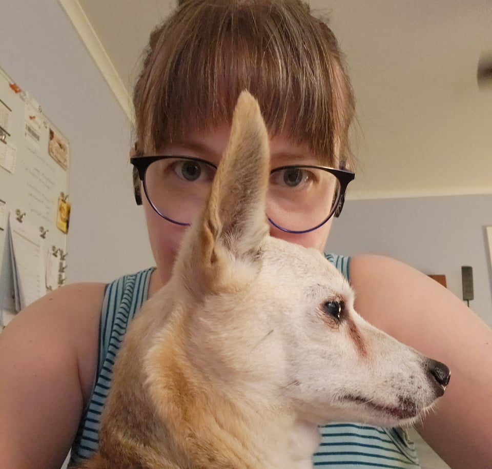 Photo of Sarah’s face mostly covered by the profile of a geriatric Chihuahua.