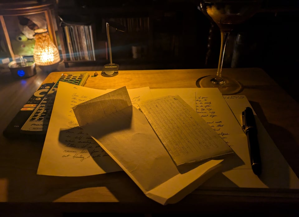 A pile of letters and stationery illuminated by a small reading light