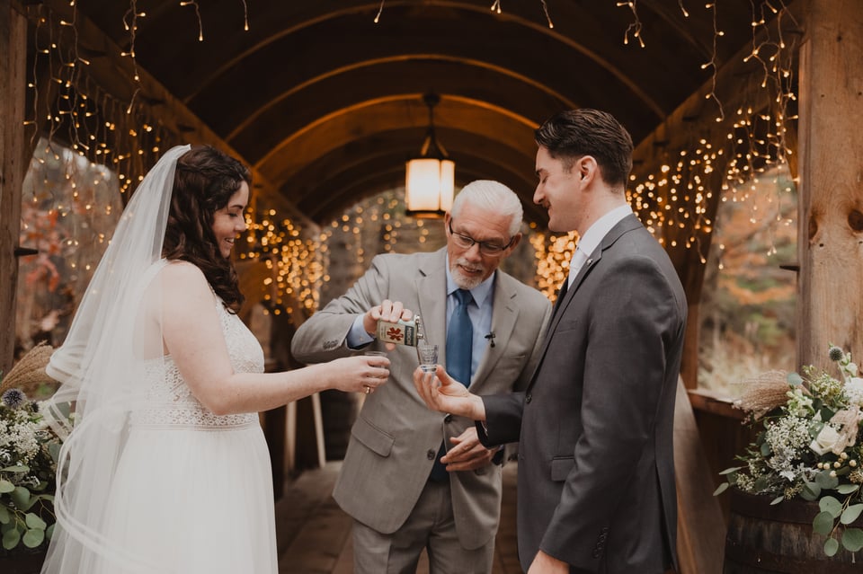 a bride and groom being poured shots at their wedding ceremony