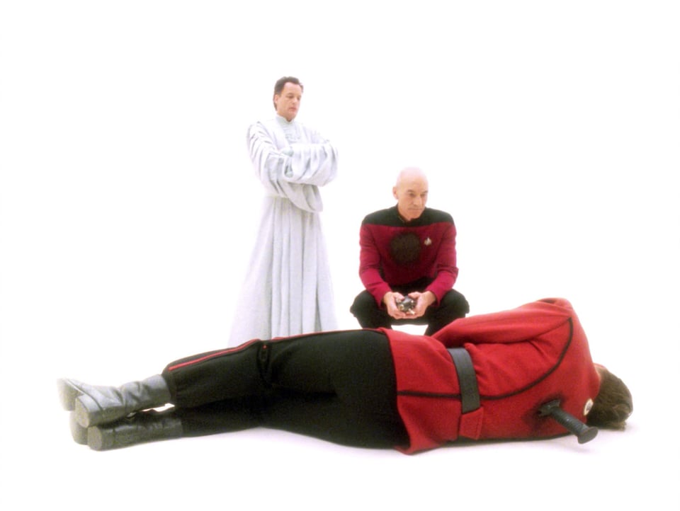 Q and Picard are in a white, heavenly void. Picard is crouched over the body of his younger self. The younger version of Picard has been stabbed in the back.