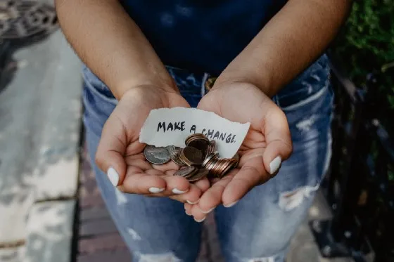a woman's hands holding coins and a note that says make a difference