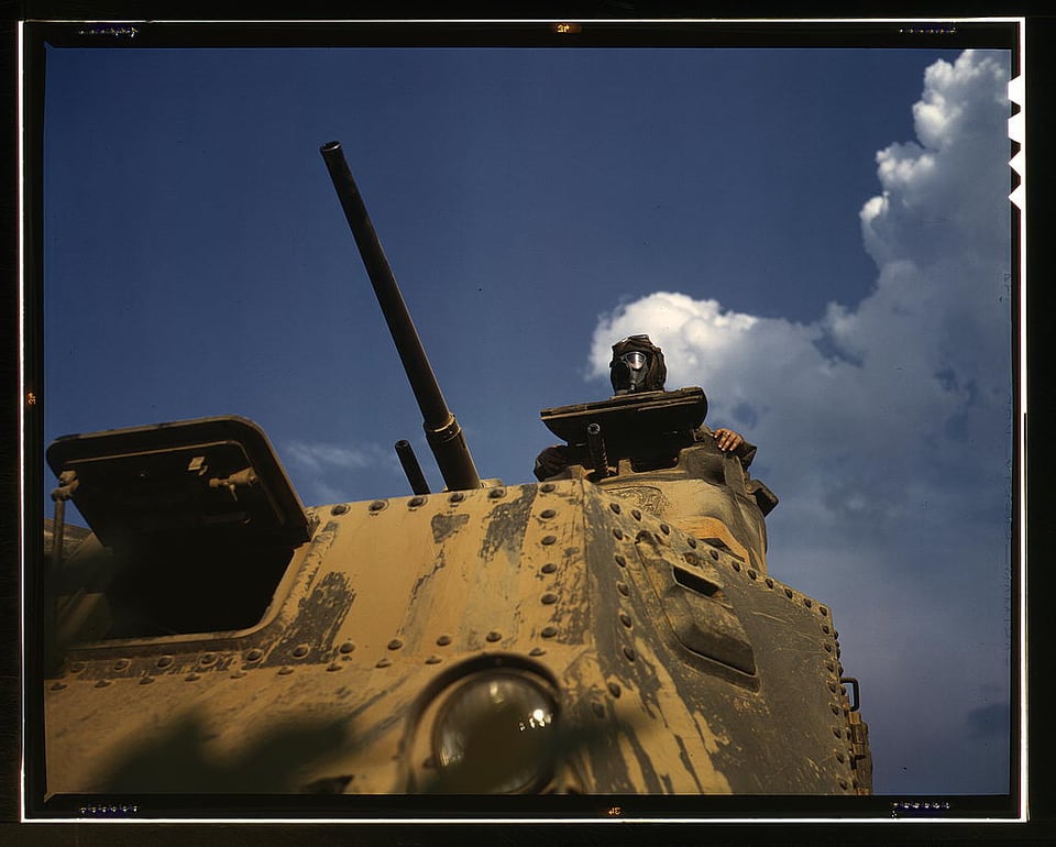 a man looks out of a tank against a blue sky