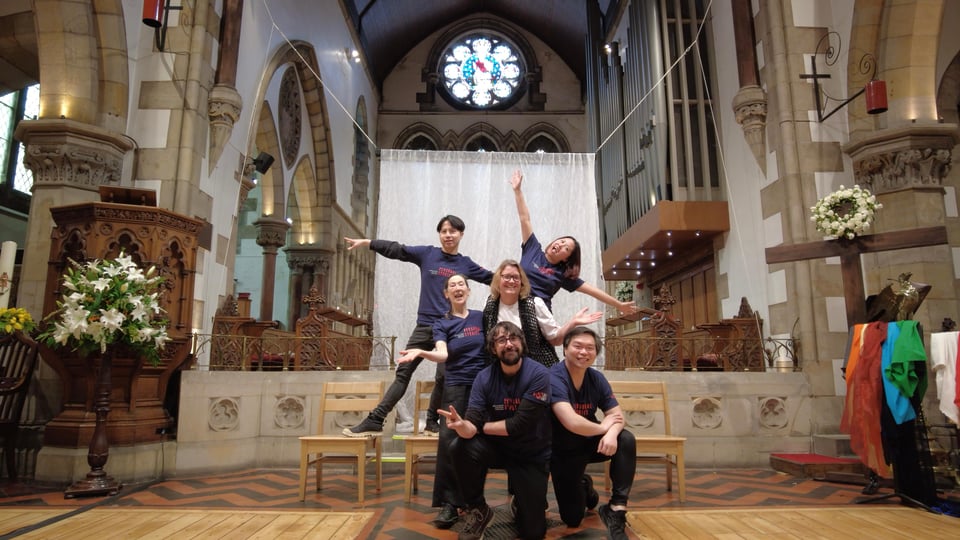 a playback theatre troupe posing inside a church after a performance.