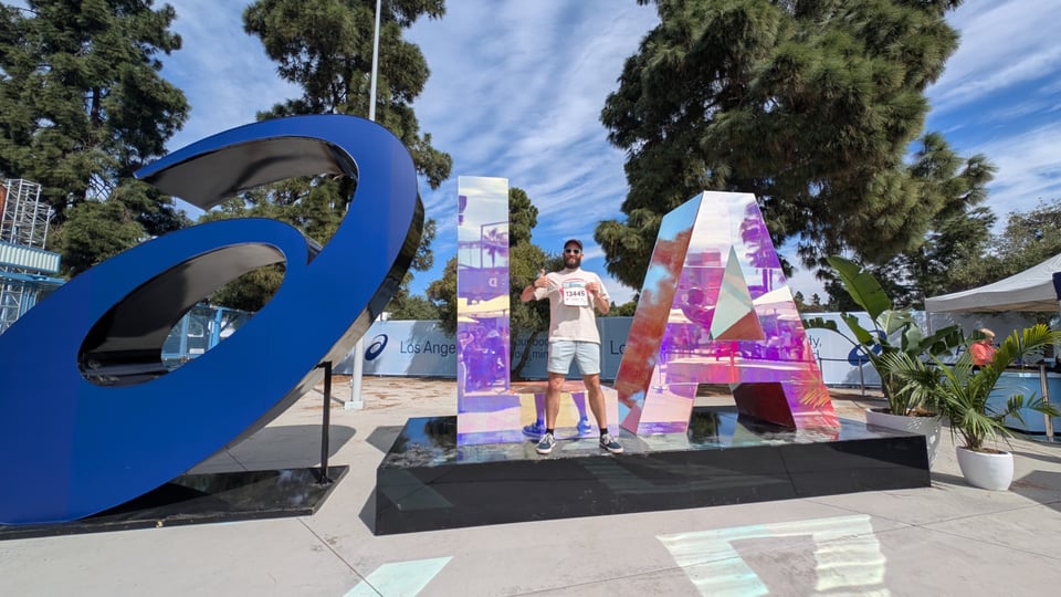 Myself at the LA Marathon expo, standing with giant mirrored letters L A.