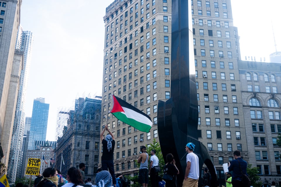 a protester waves a Palestinian flag in a small crowd in Manhattan.
