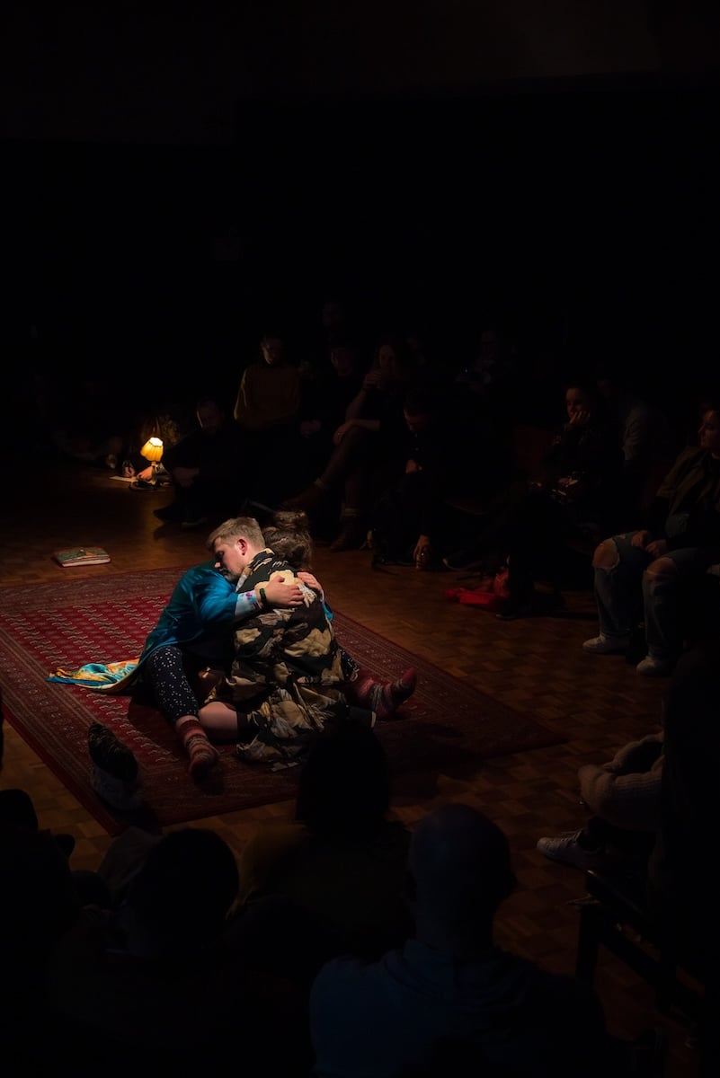 Two actors hugging in the centre of the stage.