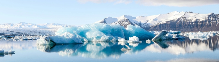 A lake with a large icy glacier, and snow-capped mountains in the distance