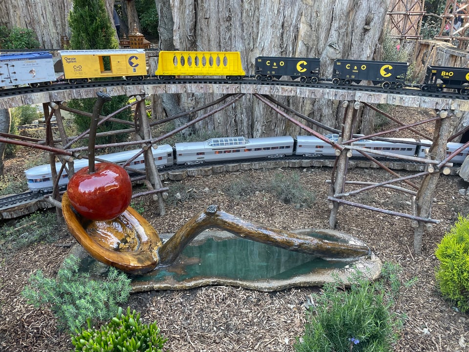 A model trains whizzes by a giant wooden spoon and cherry