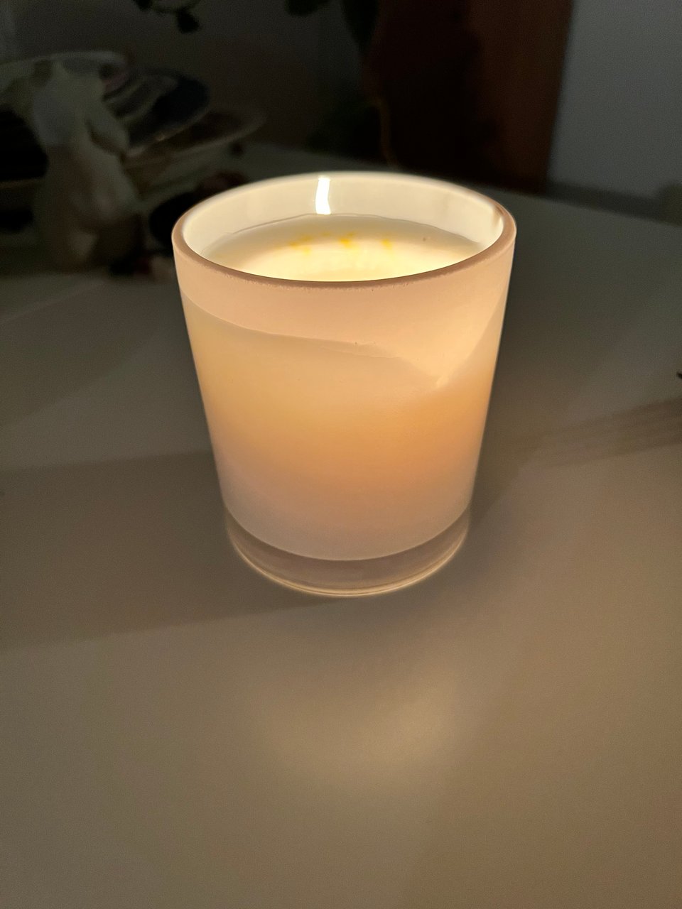 A candle in a frosted glass jar