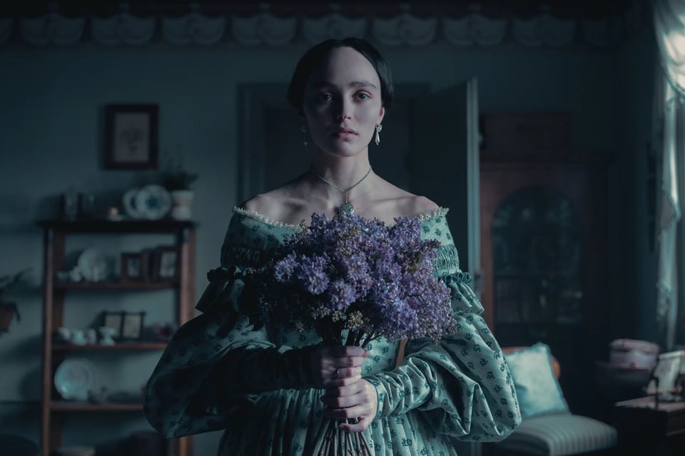 Still from the movie Nosferatu, featuring a woman holding flowers and looking sad