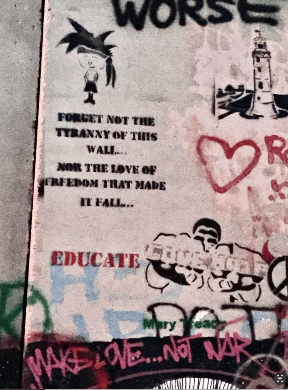 A concrete structure covered with graffiti that includes the words EDUCATE and MAKE LOVE... NOT WAR, a heart, and other images such as a lighthouse
