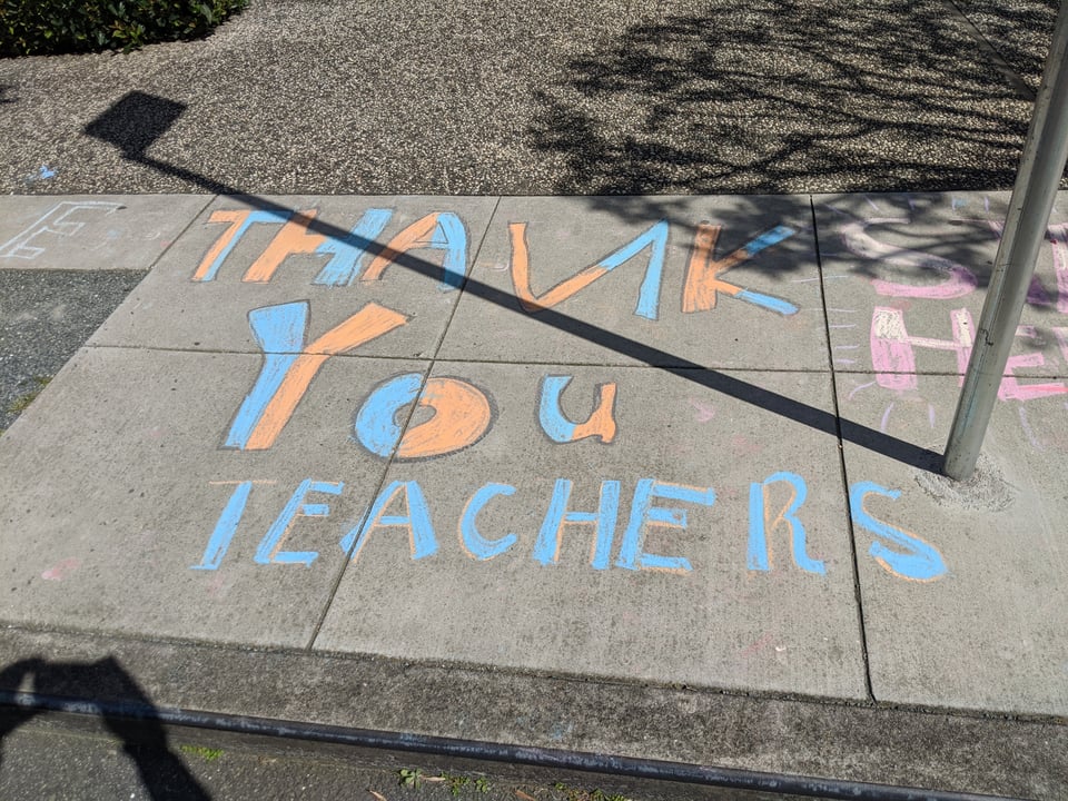 A sidewalk featuring blue-and-orange chalk art that reads Thank You TEACHERS