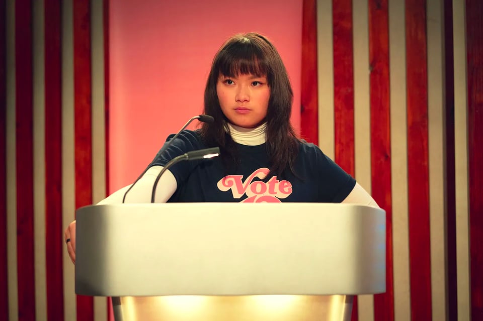 O standing behind a lectern in Sex Education