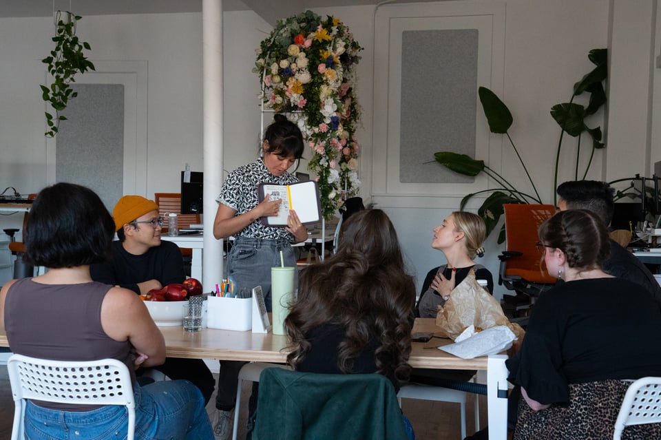 Livvy showing a drawing to a group around the table.