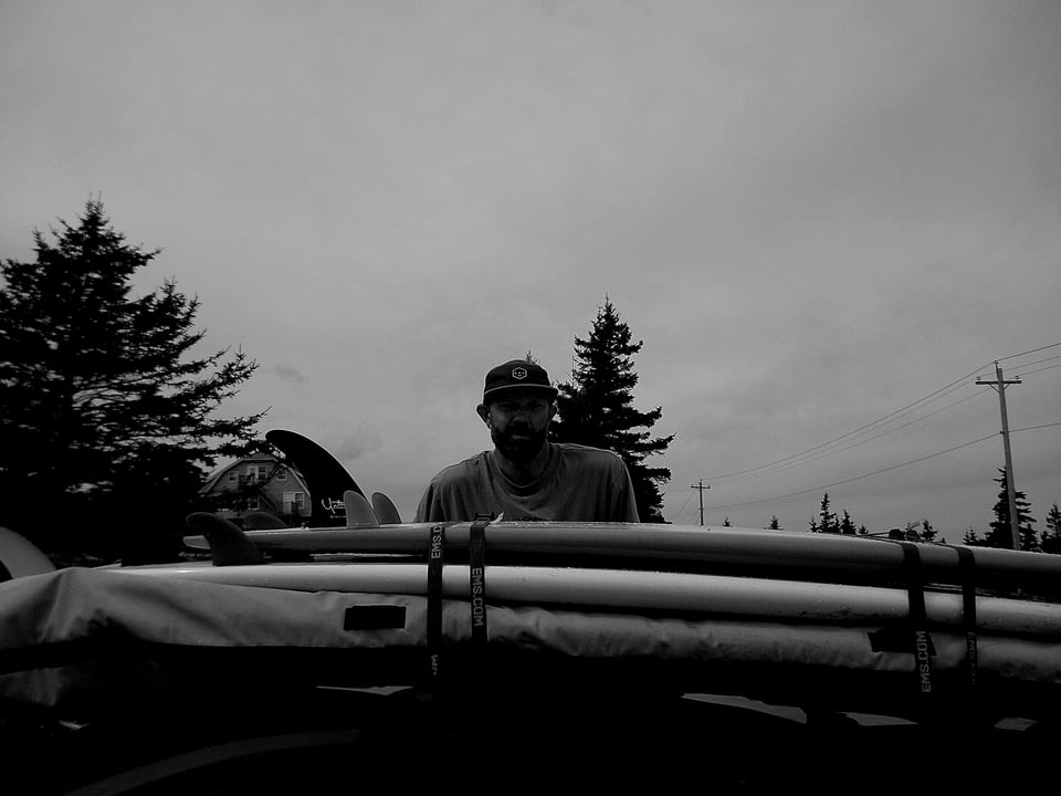 dave is in a black and white photo strapping boards to the roof of his car