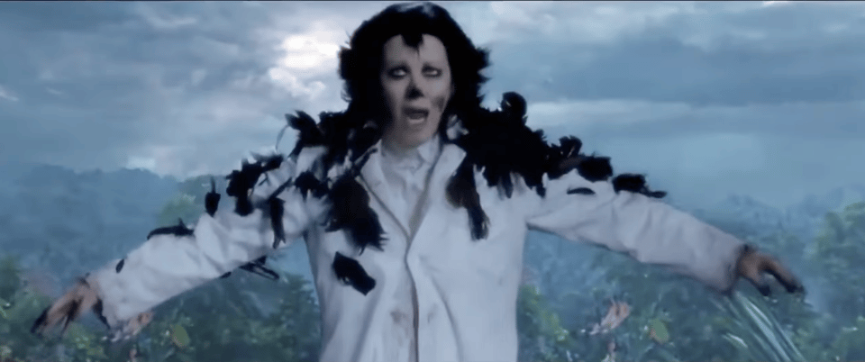 Moira Rose in The Crows Have Eyes, wearing a white lab coat but somehow also partly covered with black feathers as she appears to be mutating.