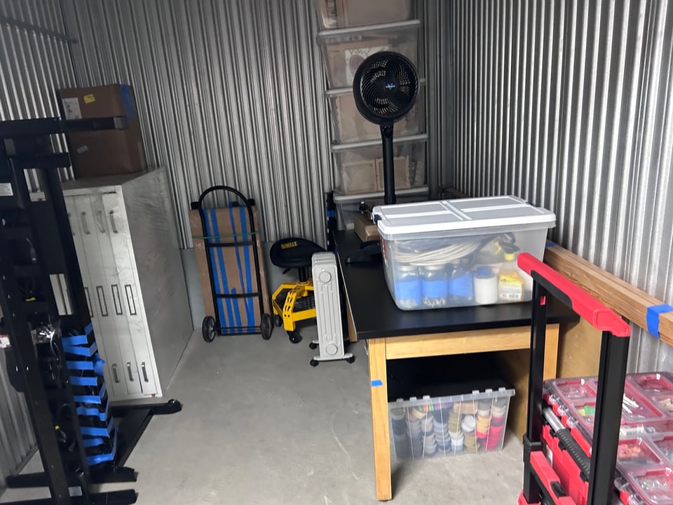 A bunch of art studio equipment and furniture in a storage unit.
