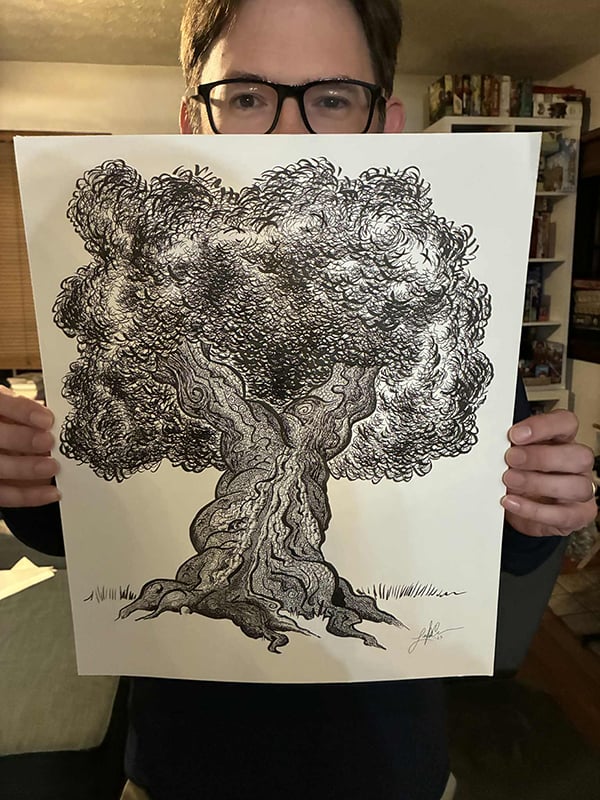 A photograph of me, Leighton Connor, standing in my living room, but you can't see much of me because I'm holding in front of me a large drawing, black and white, ink on white paper, of a tree.