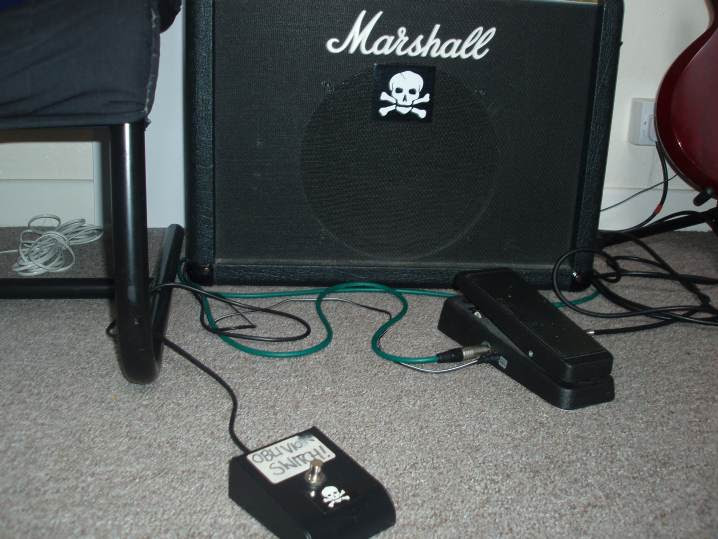 A photo of a guitar amplifier with two pedals plugged in, including a footswitch labelled "OBLIVION SWITCH!"