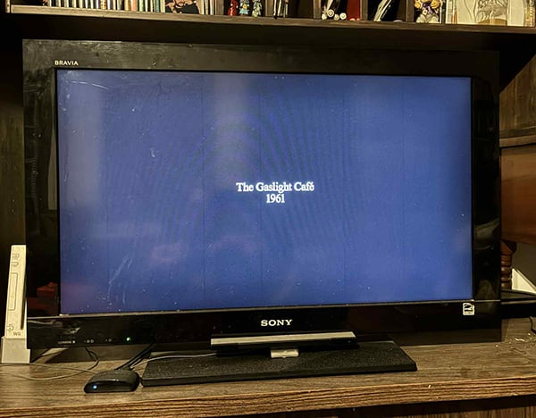 A television with a blank screen and the words The Gaslight Cafe 1961 in white letters