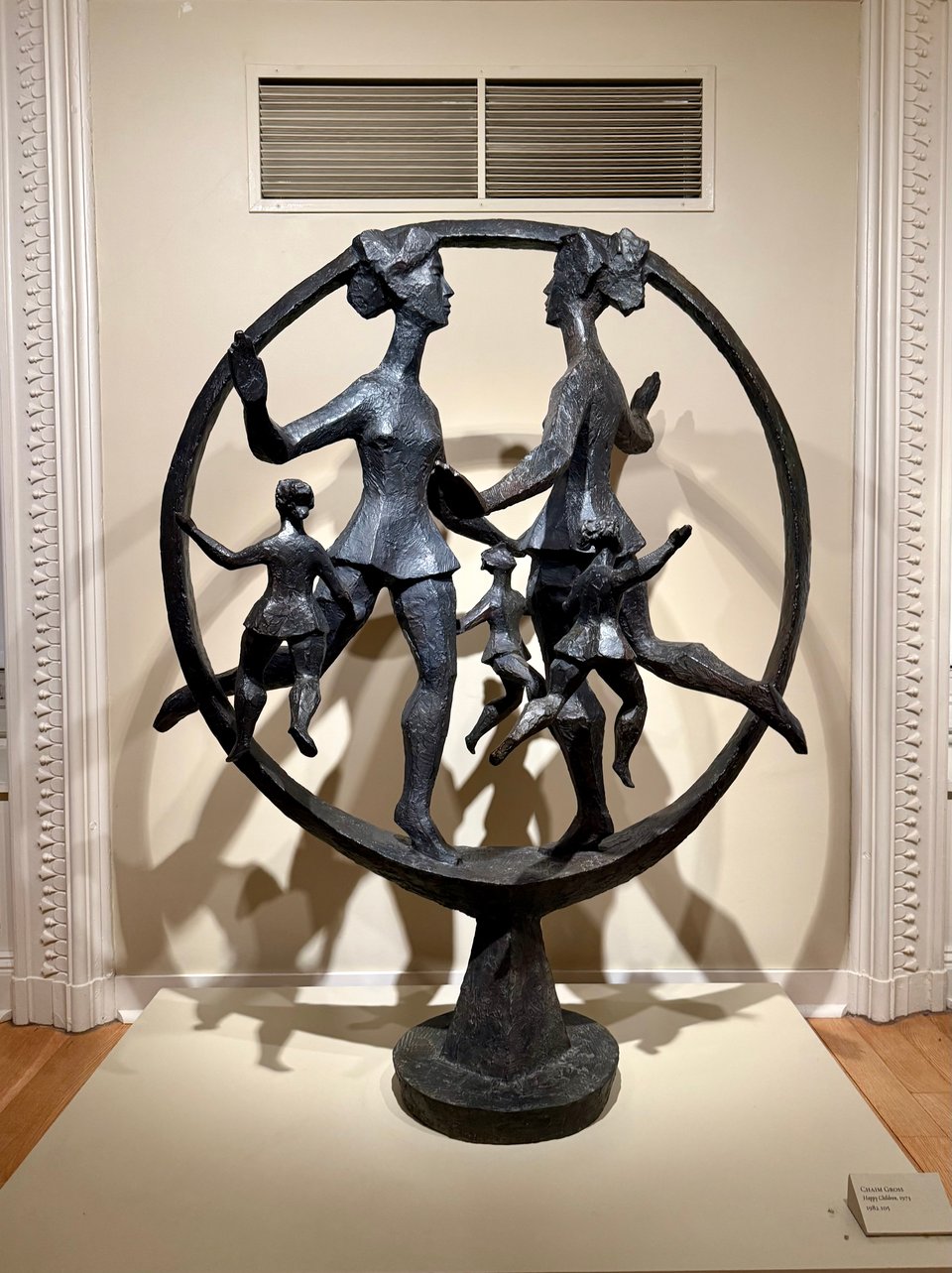 photo of a bronze sculpture of a ring with women large and small in light/dance poses