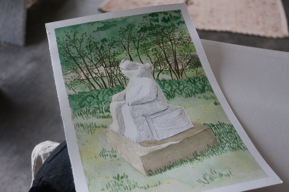 photo d'une aquarelle représentant une sculpture d'ours assis face au soleil, avec un grand sourire, dans un parc arboré, avec la montagne dans le fond