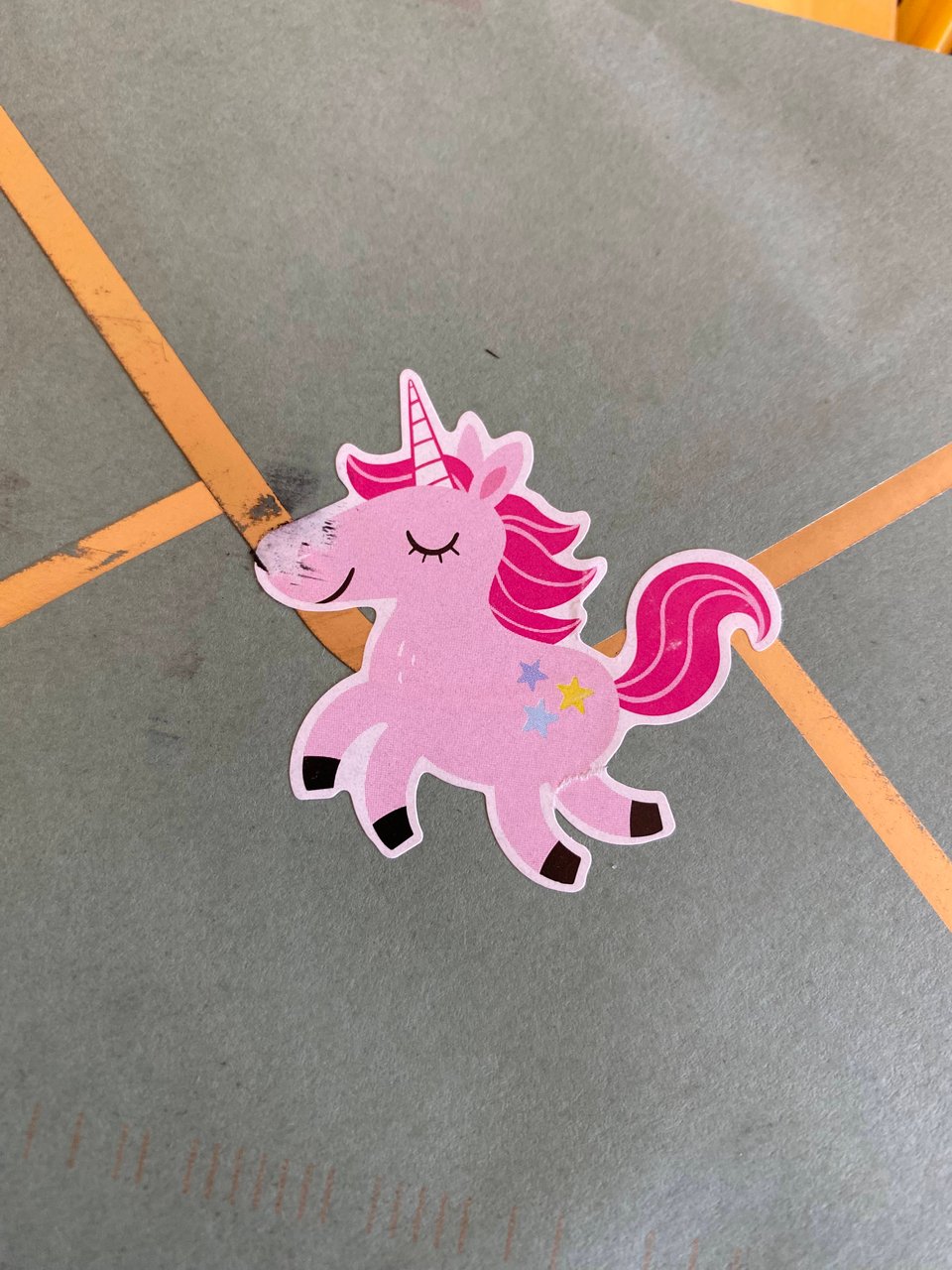 a pink unicorn sticker on the back of an envelope