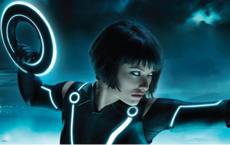 A promo image from Tron Legacy featuring a woman with a classic bob, wearing a fetishy latex outfit covered with glowy raver stripes, holding a lit-up frisbee