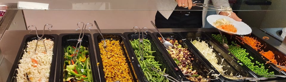 A line of dishes containing a colourful array of fresh vegetables and pulses in a Swedish school canteen