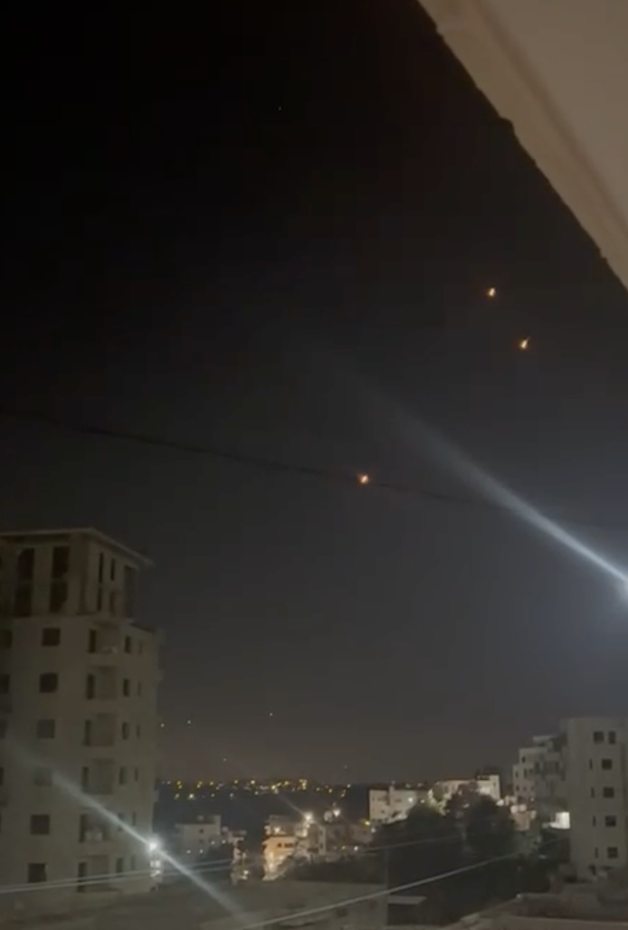 A view of the night sky from a balcony, with three lights that are missiles from Iran