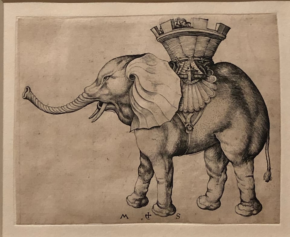 Charming print of an elephant wearing a harness in the shape of a fortress on its back. A couple of soldiers’ heads peek out of the top.