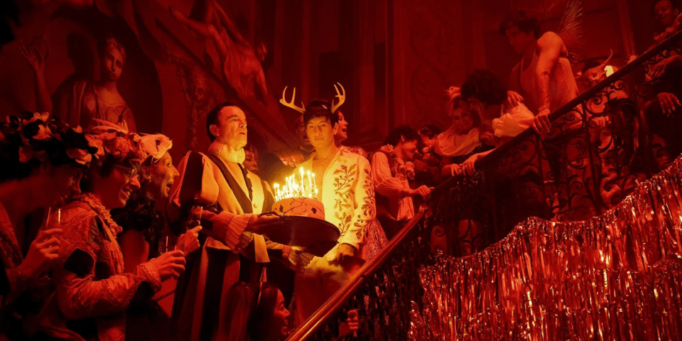 A load of posh people celebrate a birthday on a staircase.