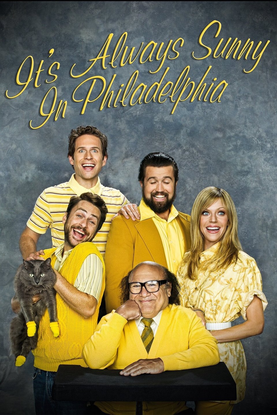 Always Sunny promo photo featuring Charlie with a cat wearing kitten mittens, Frank, Dennis, Mac and Dee