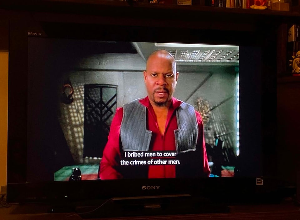 A picture of my television with the image of Captain Benjamin Sisko staring at the camera and the closed captioning says "I bribed men to cover the crimes of other men."