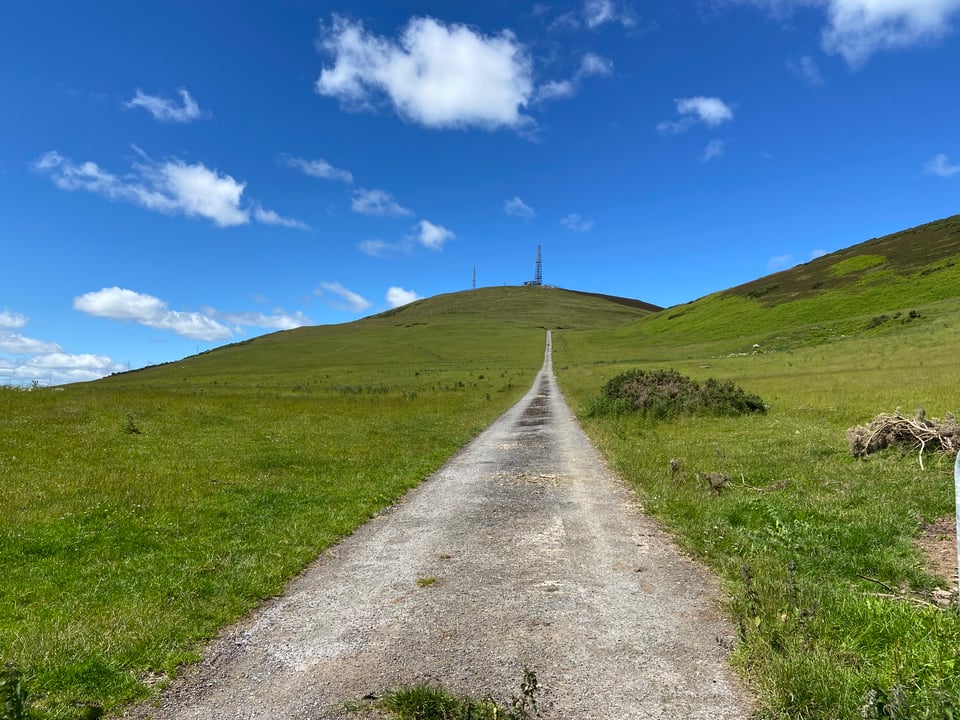 a very straight road up a grassy hill