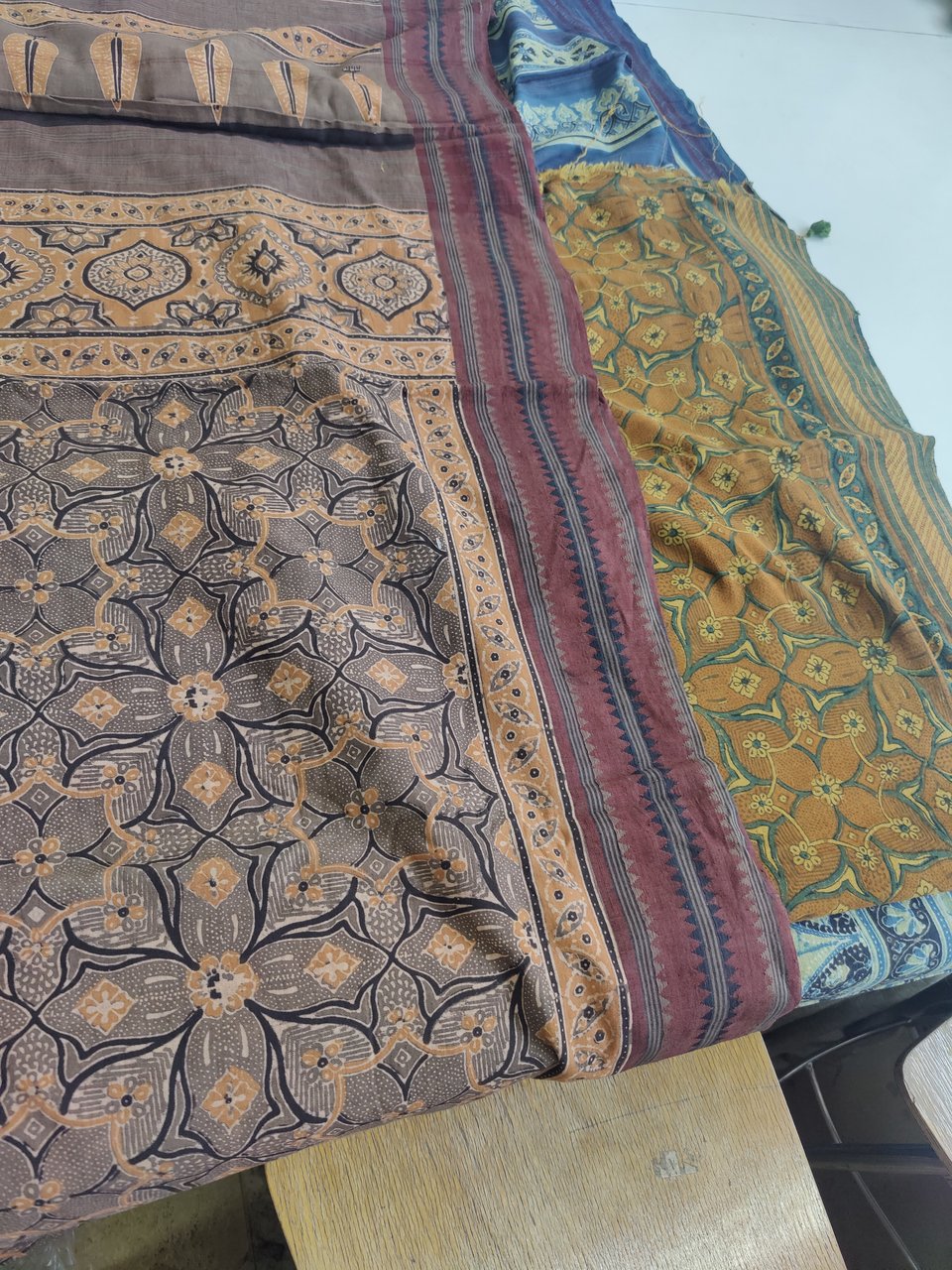 Two block-printed cotton sarees side-by-side, with the same design but in different colours.