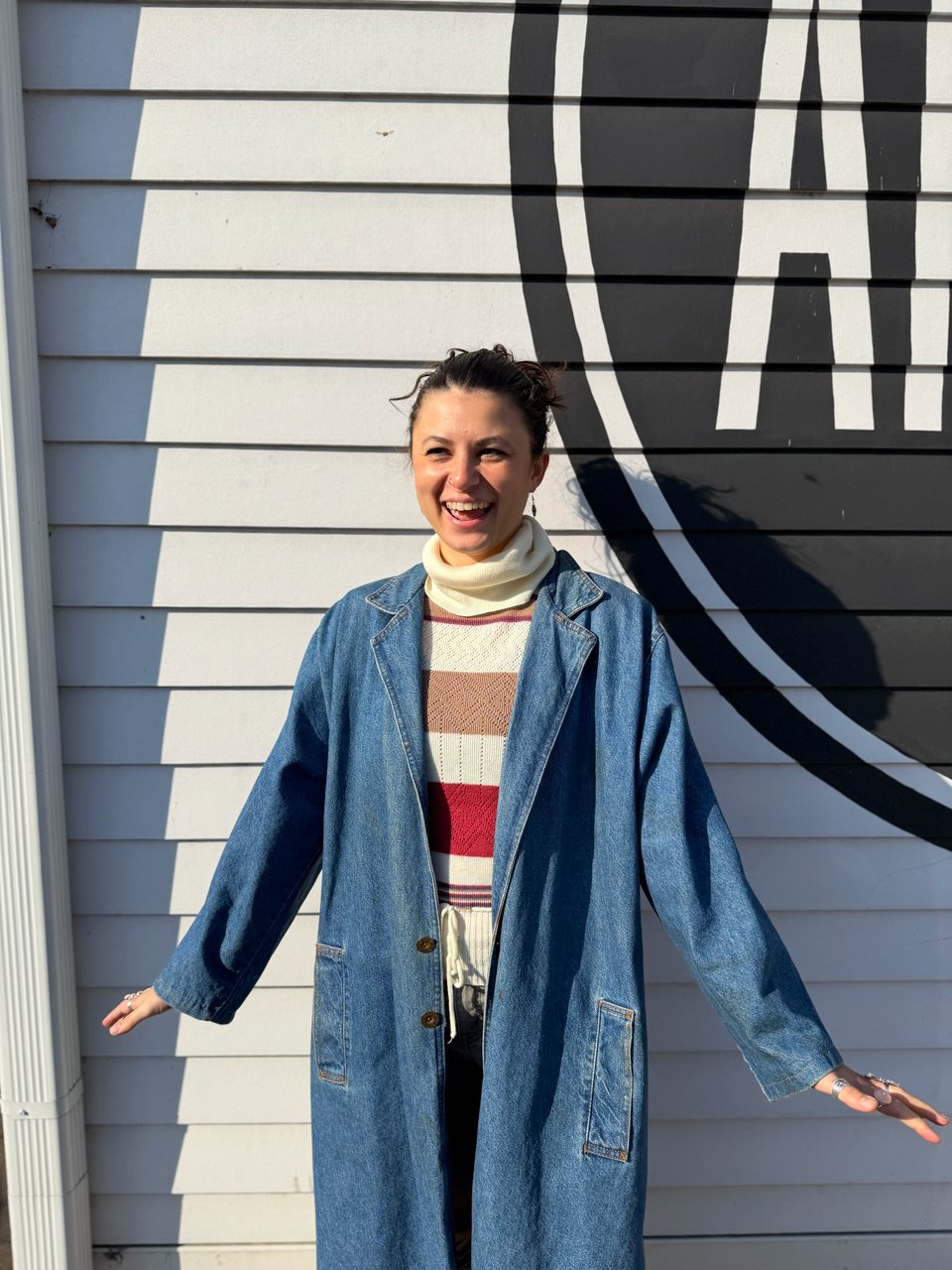 A photo of Sierra Nuckols standing on the side of Amelia's bakery with her hands flared out to the side