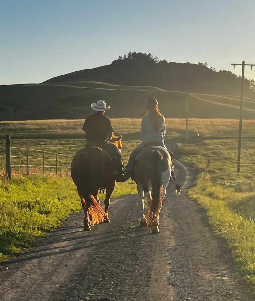 Our cowboy and our daughter on horses in the setting sun.