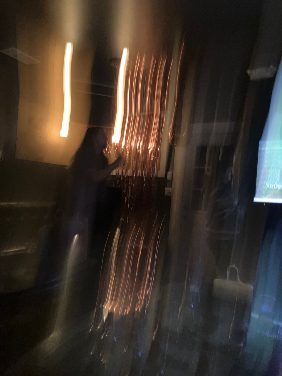 A blurry image of a man singing karaoke in a private room.