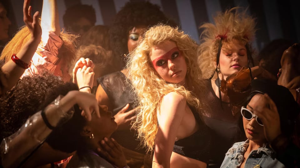 Mia Goth as Maxine Minx is all dolled up and dancing at a club.