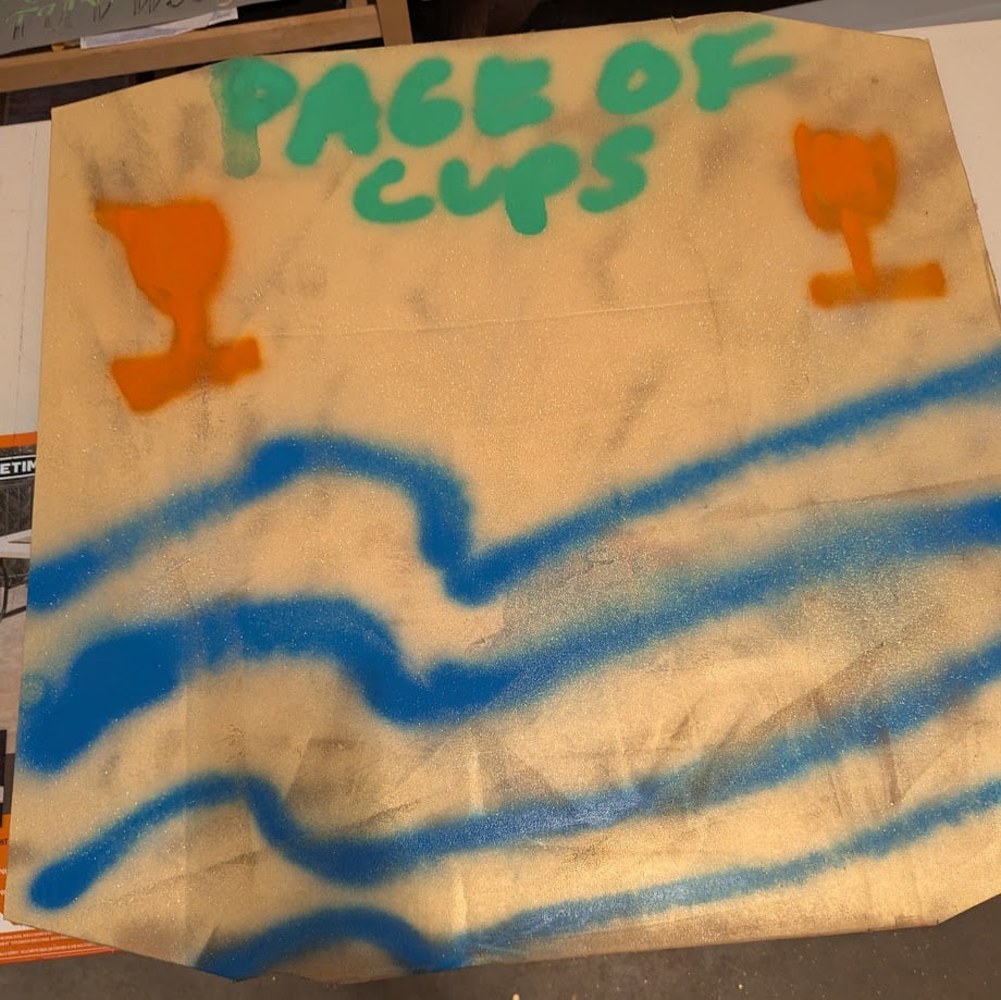 A spray painted Page of Cups backdrop.