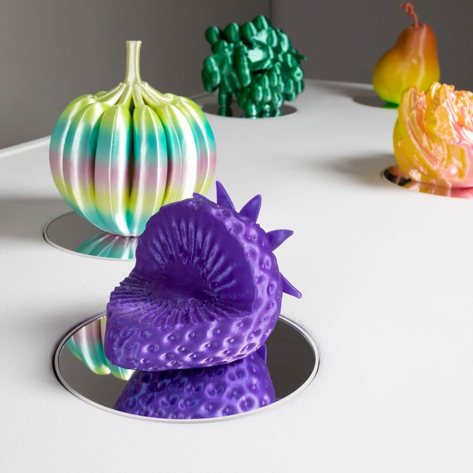Fruit sculptures resting on mirrored spinning platforms