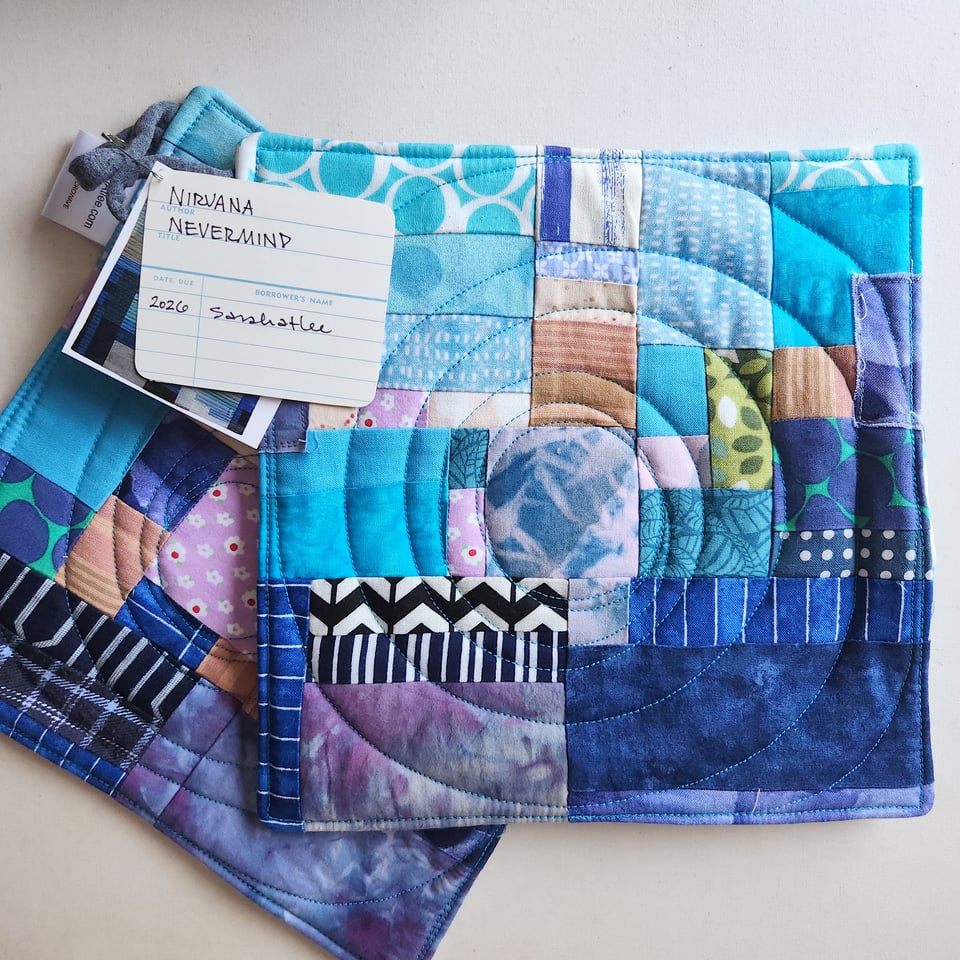 Photo of a pair of finished quilted potholders. The design is Sarah's interpretation of the cover of Nirvana's 1991 album, Nevermind.