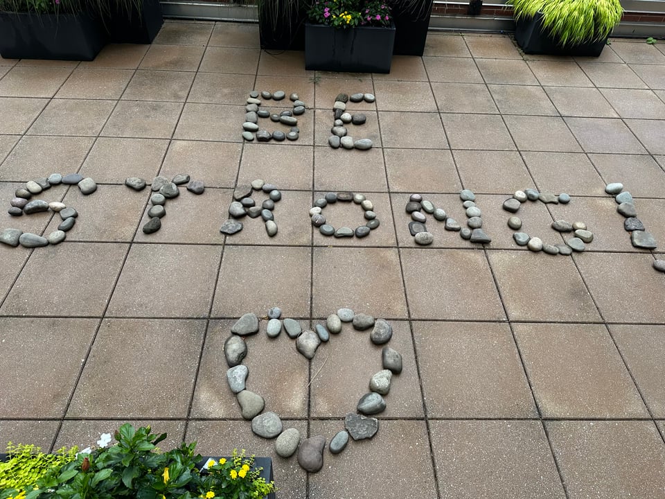 photo of concrete patio tiles with the words BE STRONG! and a heart made out of stones