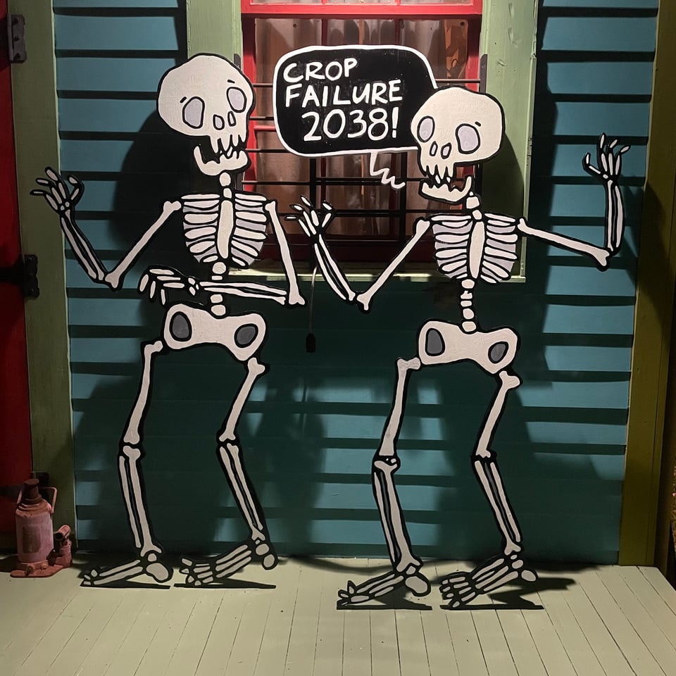 painting of two large skeletons, one saying 'crop failure 2038!'