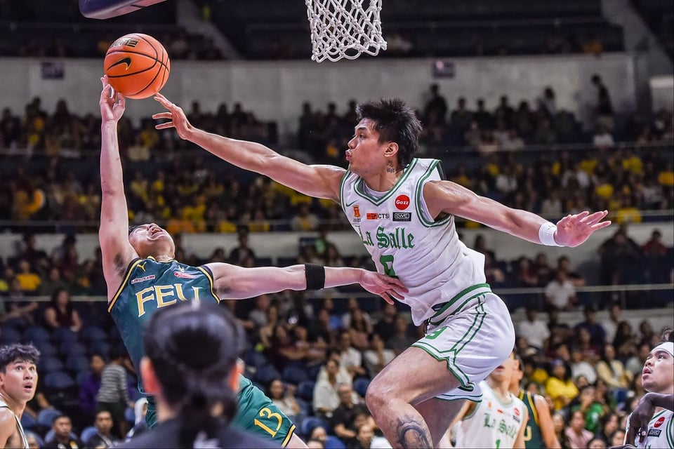 a filipino basketball player from de la salle university, big ol' wingspan, blocks a shot while a crowd watches on