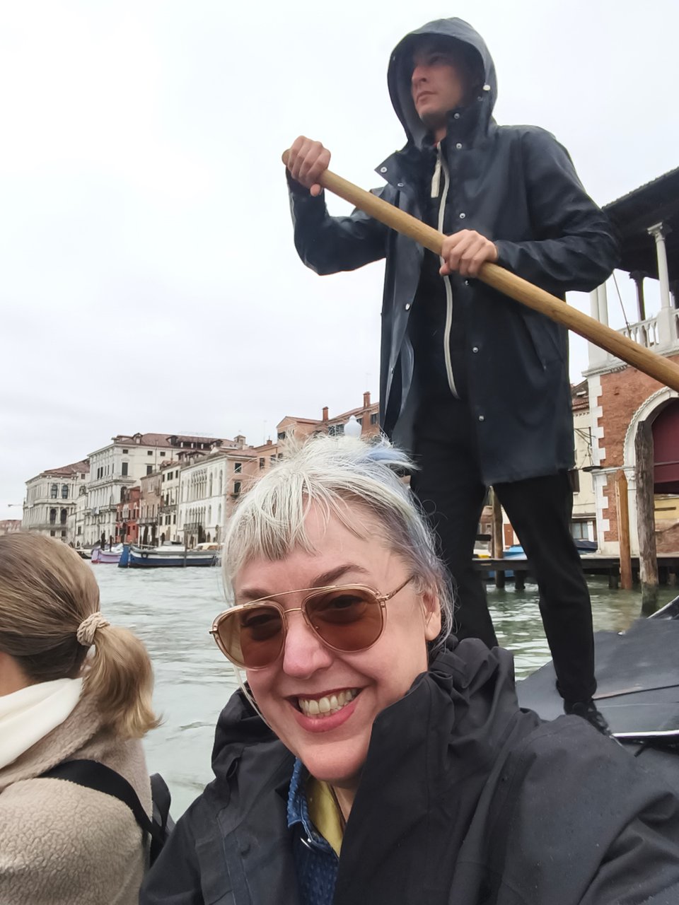 rachael in a gondola grinning, a man standing and rowing behind her