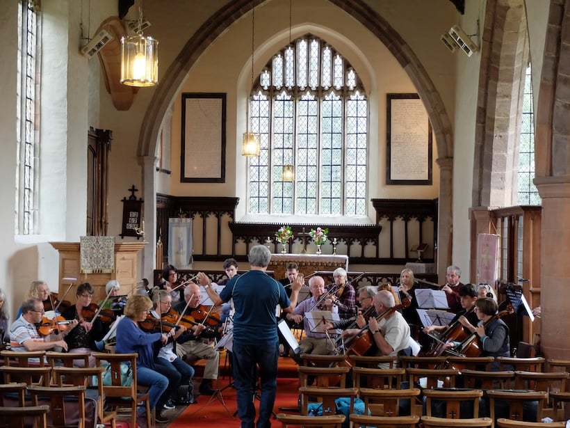 An orchestra rehearses in a church.